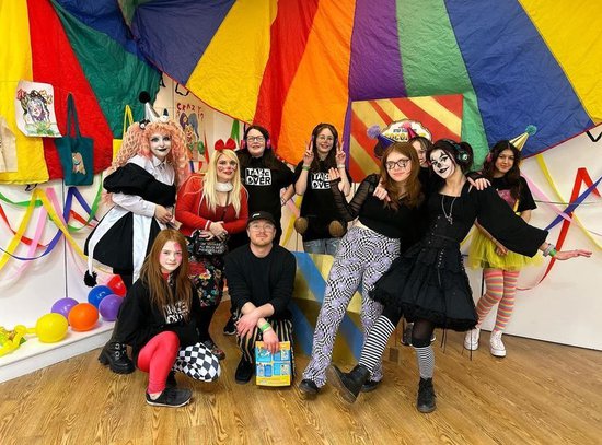 A group of people dressed up as circus artists stand together